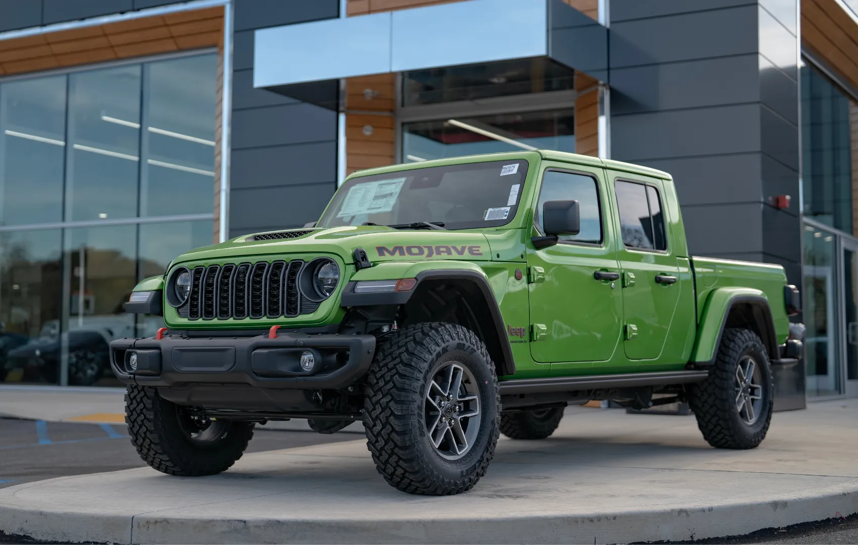 Green Jeep Gladiator sitting in front of C. Harper CDJR Mon Valley dealership in Belle Vernon, PA